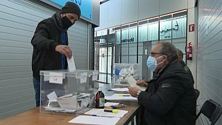 A masked voter places his ballot in a polling station in Barcelona, Catalonia, Spain