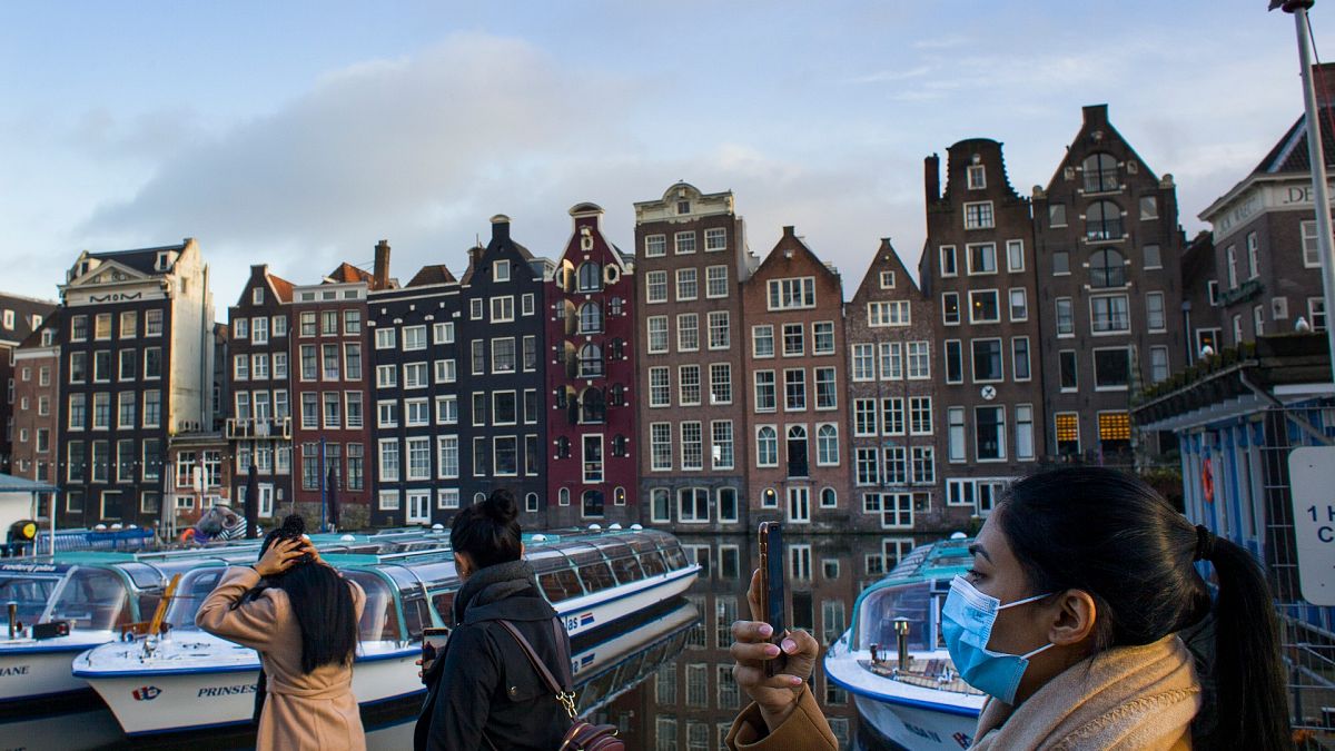 Maszkos nő fényképezi a leállított turistahajókat Amszterdamban 2021. február 4-én