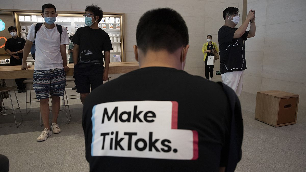 رجل يرتدي قميصاً يروج لـ تطبيق تيك توك في متجر آبل في بكين، الصين