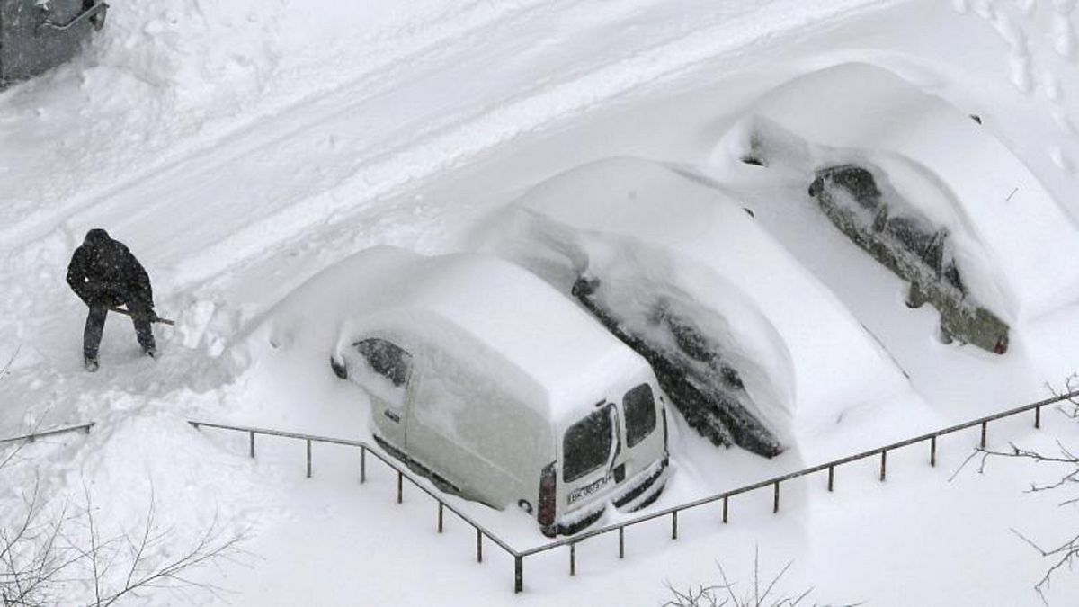 سائق يزيل الثلوج المكدسة حول سيارته في كييف ـ أوكرانيا