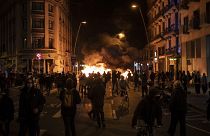 People gather next to a burning barricade during clashes after a protest condemning the arrest of rap singer Pablo Hasél in Barcelona, Spain, Wednesday, Feb. 17, 2021.