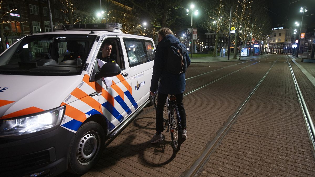 Dutch police check the papers of a man and his reason for breaking curfew in the otherwise deserted Rembrandt Square in the centre of Amsterdam, Saturday, Jan. 23, 2021. 