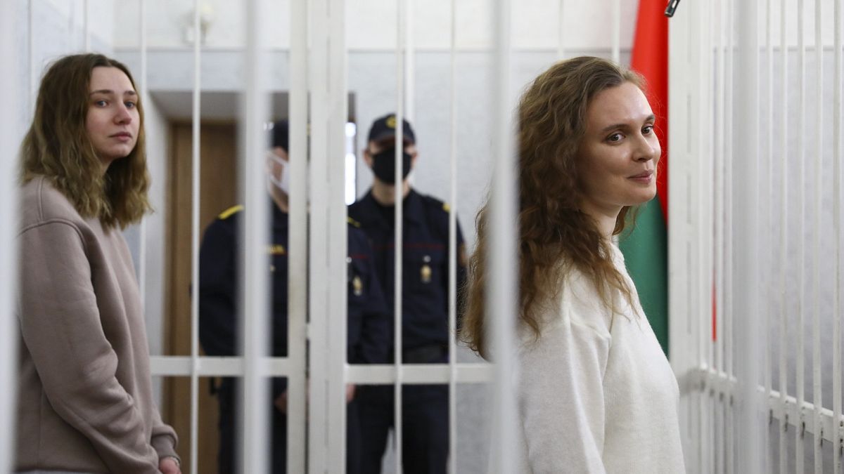 Journalists Katsiaryna Andreyeva, right, and Daria Chultsova stand inside a defendants' cage in a court room in Minsk, Belarus, Thursday, Feb. 18, 2021.