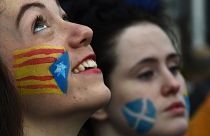 Sui volti di queste due donne la bandiera catalana, Estelada (a sinistra) e quella scozzese, Saltire: siamo in una manifestazione di sostegno alla causa catalana a Glasgow