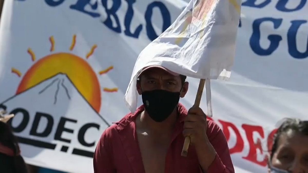 Un manifestante se protege del sol con una pancarta de tela durante la protesta contra el presidente de Guatemala, Alejandro Giammattei, en Ciudad de Guatemala.