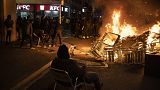 A man sits on a chair in front of a burning barricade during a protest condemning the arrest of rap singer Pablo Hasél in Barcelona, Spain, Friday, Feb. 19, 2021.