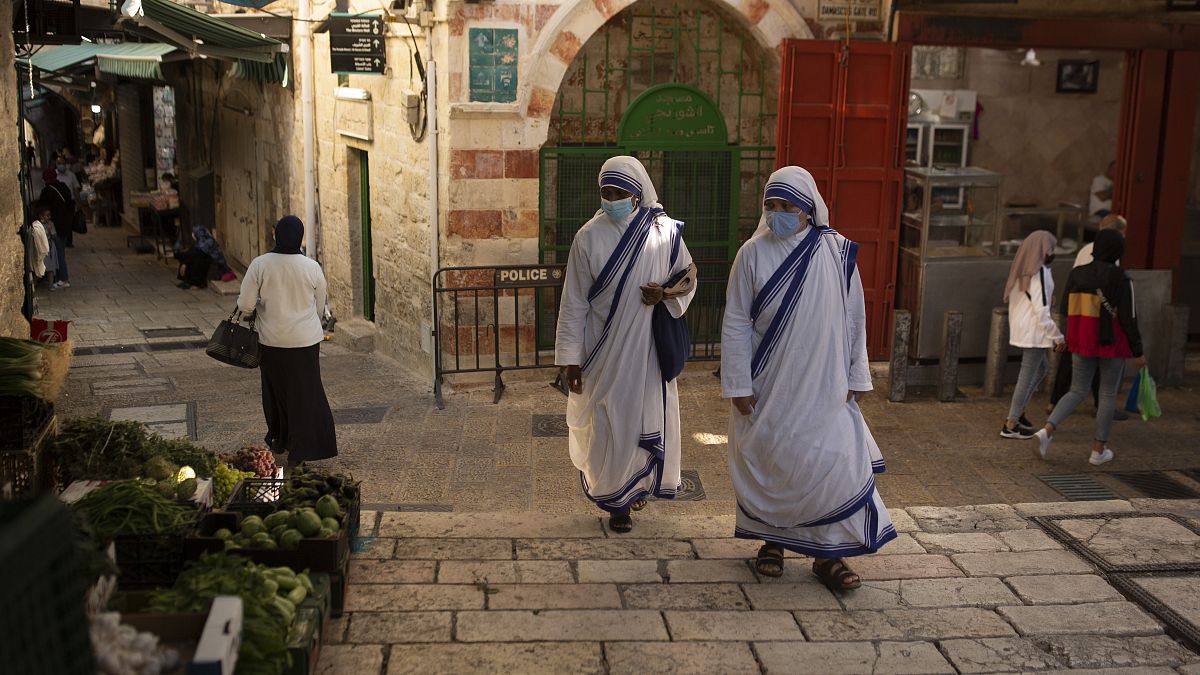 Maszkot viselő katolikus apácák sétálnak a jeruzsálemi óvárosban 2020. október 21-én