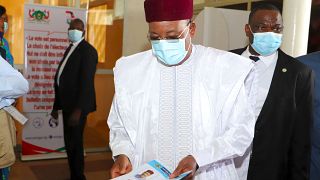 Niger's outgoing president Mahamadou Issoufou (C) prepares to cast his vote at the polling station during Niger's presidential election run-off, in Niamey. February 21, 2021.