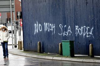 A woman walks past past graffiti with the words 'No Irish Sea Border' in Belfast city centre, Northern Ireland, Wednesday, Feb. 3, 2021. 