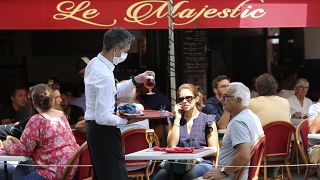 A bartender brings drinks to customers in a cafe of Saint Jean de Luz, southwestern France, Tuesday June 2, 2020.