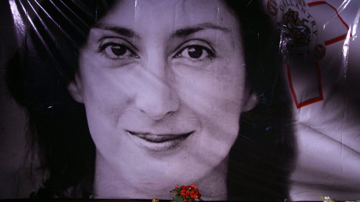  flowers and a candle lie in front of a portrait of slain investigative journalist Daphne Caruana Galizia during a vigil outside the law courts in Valletta, Malta