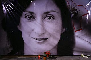  flowers and a candle lie in front of a portrait of slain investigative journalist Daphne Caruana Galizia during a vigil outside the law courts in Valletta, Malta