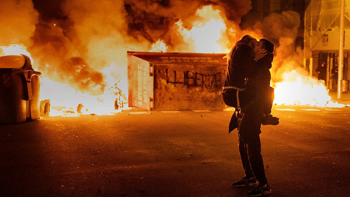 A couple kiss in front of a burning barricade in Barcelona at a protest condemning the arrest of Pablo Hasél