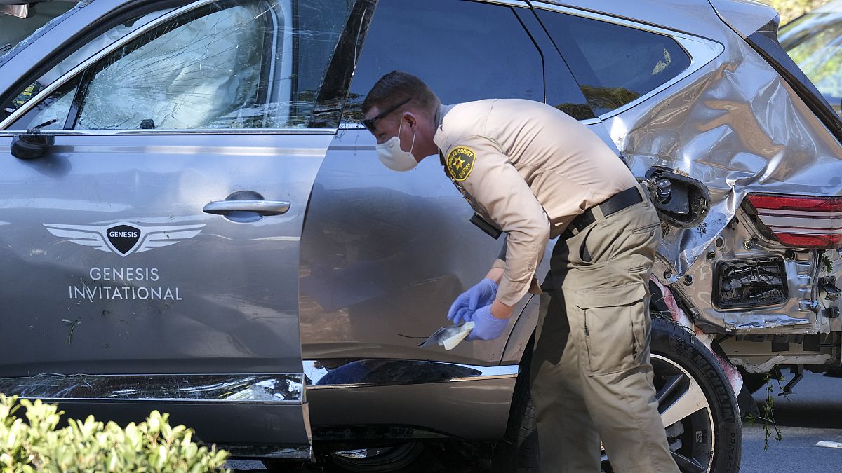 A law enforcement officer looks over a damaged vehicle following a rollover accident involving golfer Tiger Woods, Tuesday, Feb. 23, 2021, in the Rancho Palos Verdes suburb.