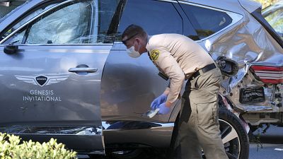 A law enforcement officer looks over a damaged vehicle following a rollover accident involving golfer Tiger Woods, Tuesday, Feb. 23, 2021, in the Rancho Palos Verdes suburb.