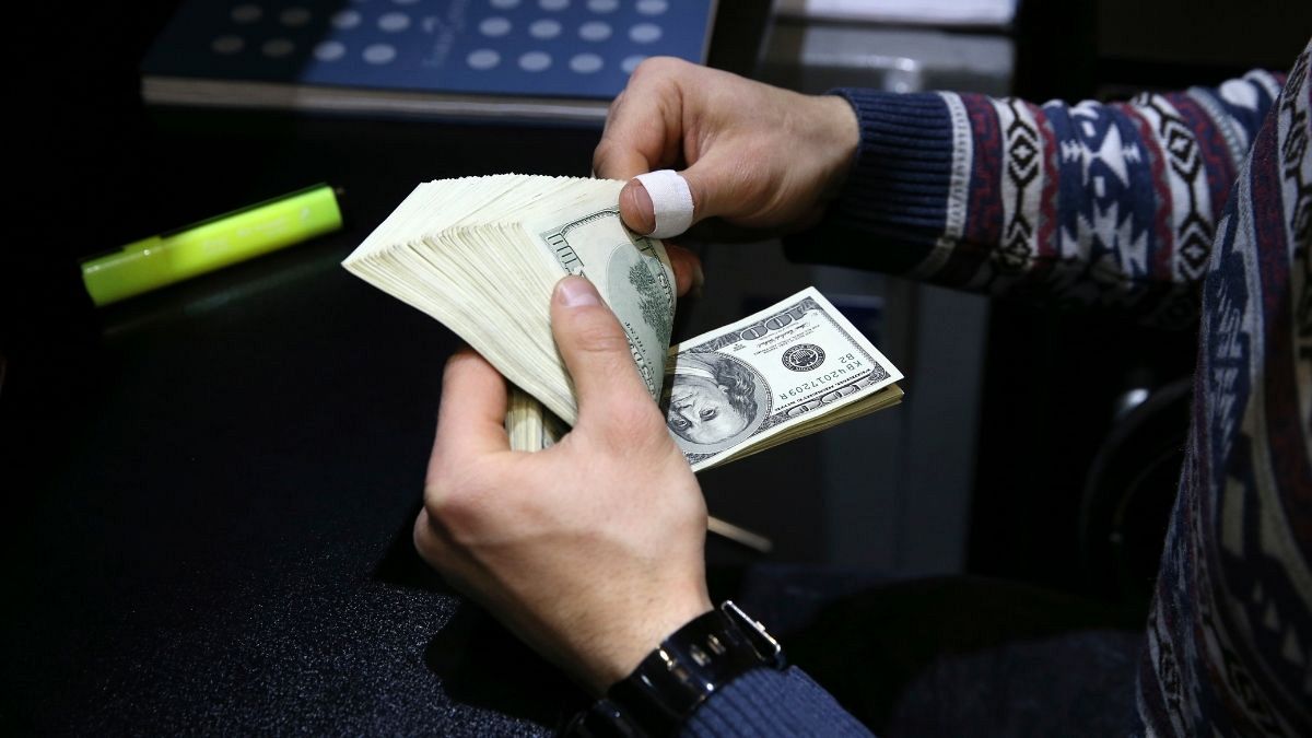 یک صراف ایرانی در حال شمارش دلار آمریکا