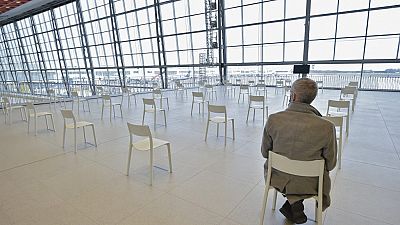A man sits in a wainting area before receiving an injection of the Covid-19 vaccine on the opening day of the vaccination centre at the Zaventem Skyhall in Brussels airport