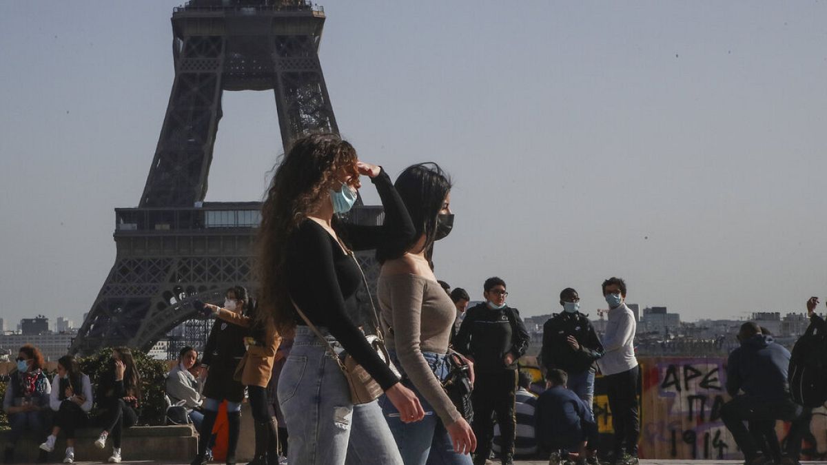 People wearing face masks to prevent the spread of coronavirus walks at Trocadero plaza near Eiffel Tower in Paris, Wednesday, Feb. 24, 2021