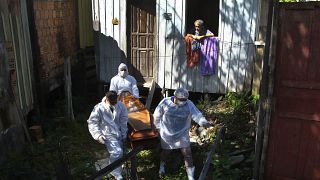 قيام عمال خدمة الجنازات العامة بإخراج جثة سيدة توفيت بسبب مضاعفات مرتبطة بـكوفيد- 19 من  منزلها، في ماناو ، ولاية أمازوناس- البرازيل