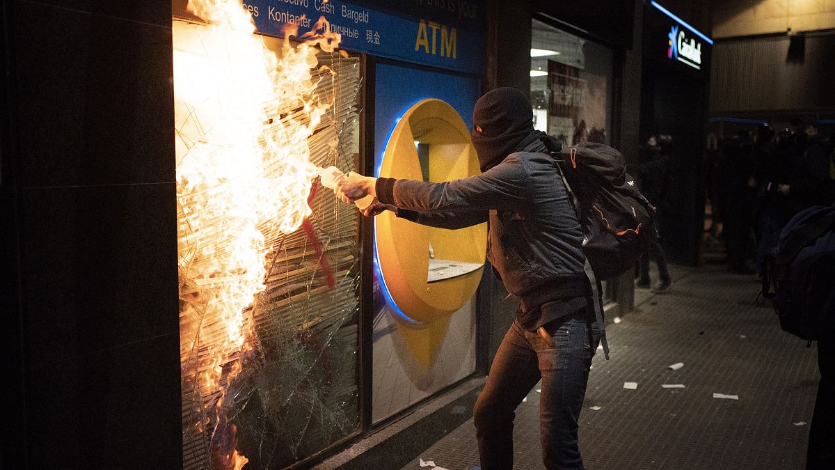 Манифестант поджигает банк в ходе протестов против заключения в тюрьму Пабло Аселя, 27 февраля 2021 г.