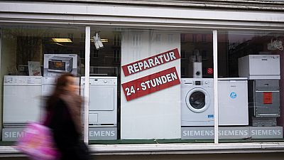 A person walks past a shop offering the repair of electronic equipment and domestic appliances in Berlin, Germany, Friday, Feb. 26, 2021.