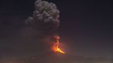 Flames and smoke billowing from a crater, as seen from the southern side of the Mt Etna volcano, tower over the city of Pedara, Sicily, Wednesday night, Feb. 24, 2021.
