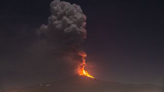 Flames and smoke billowing from a crater, as seen from the southern side of the Mt Etna volcano, tower over the city of Pedara, Sicily, Wednesday night, Feb. 24, 2021.