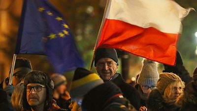 People holding a Poland and EU flags take part in a protest in Warsaw over much-criticised legislation that allows politicians to fire judges who criticize their decisions