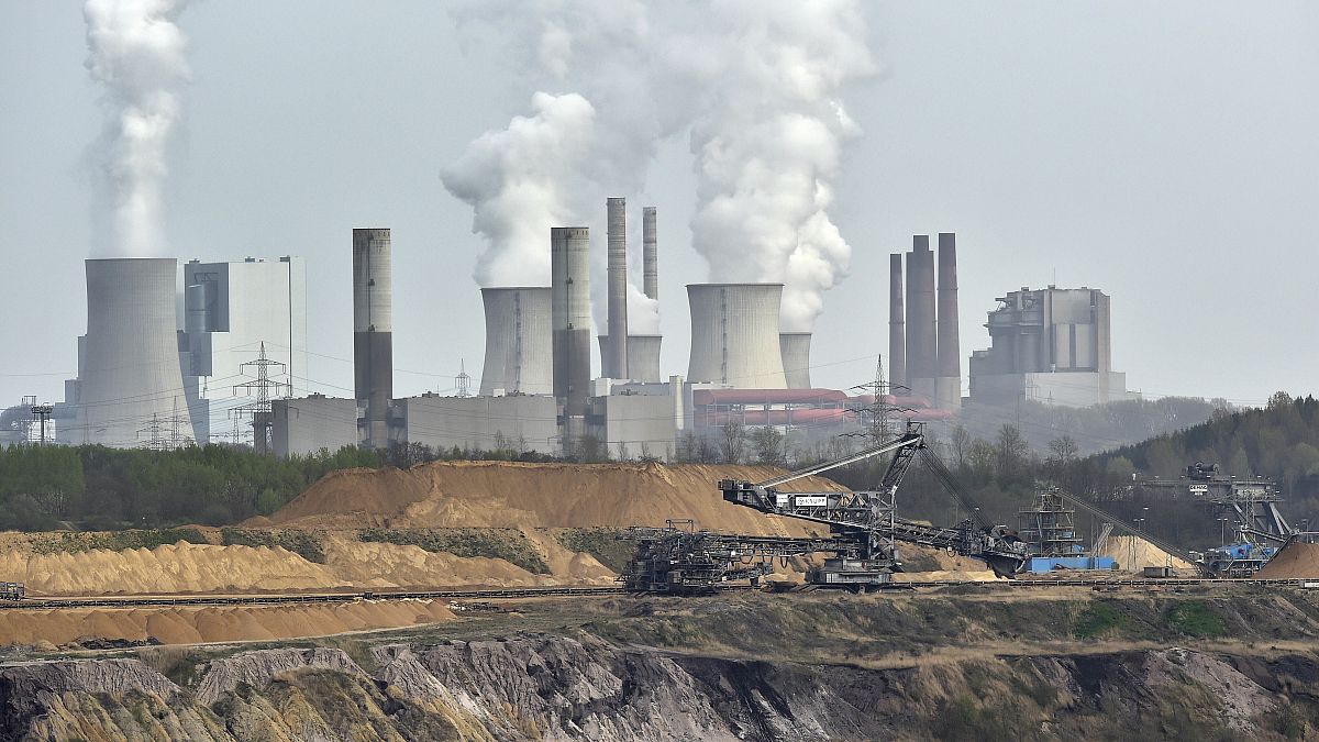 Giant machines dig for brown coal at the open-cast mining Garzweiler in front of a smoking power plant near the city of Grevenbroich in western Germany in April 2014.