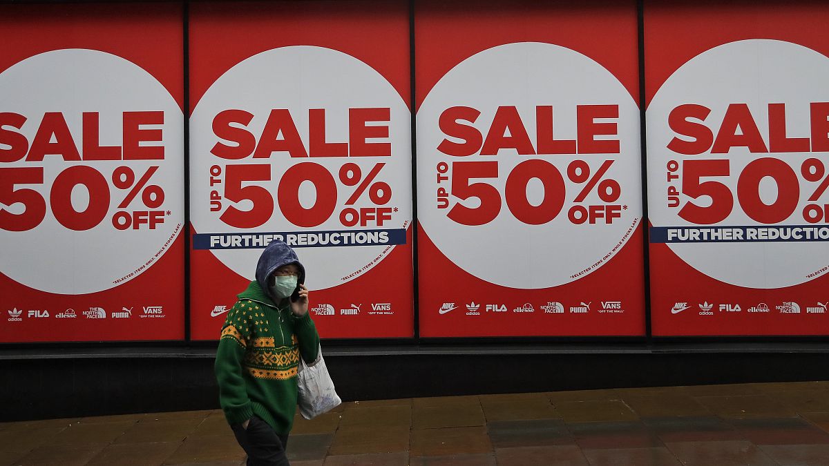 A woman wearing a face covering walks past a shop window in London, Thursday, Jan. 14, 2021 during England's third national lockdown to curb the spread of coronavirus. 