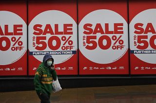 A woman wearing a face covering walks past a shop window in London, Thursday, Jan. 14, 2021 during England's third national lockdown to curb the spread of coronavirus. 