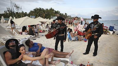 Dos mariachis hablan con turistas en Playa del Carmen, en el estado mexicano de  Quintana Roo.