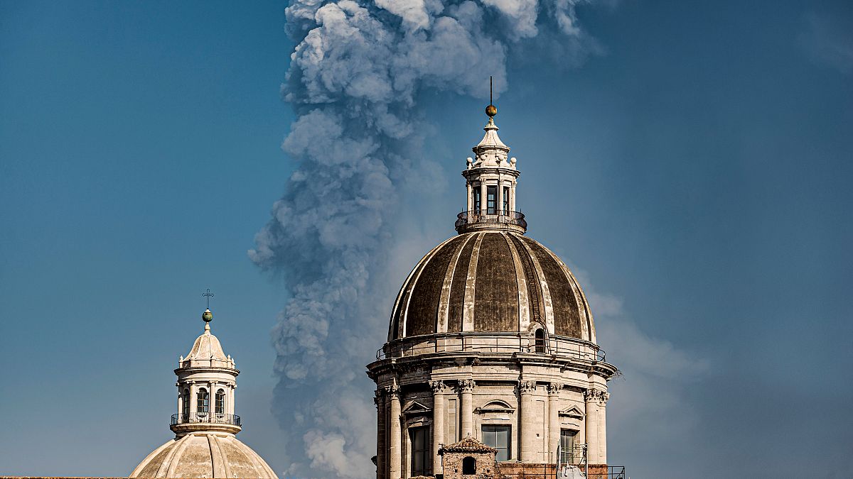 Smoke billows from a crater of Mount Etna volcano behind the dome of the Catania Saint Agatha cathedral in Catania, southern Italy. March 4, 2021.