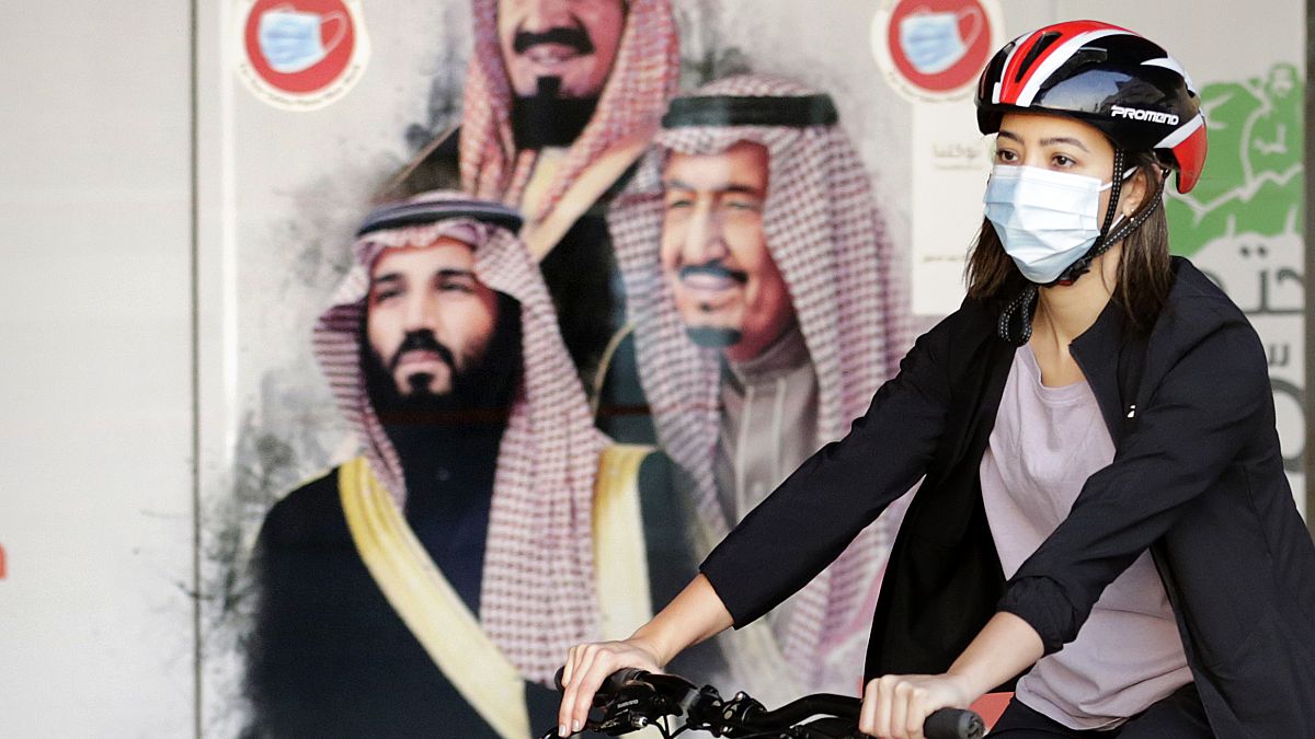 la ciclista saudita Sawsan Abdel Fattah davanti a un poster che mostra il re saudita Salman e il suo principe ereditario Mohammed bin Salman.