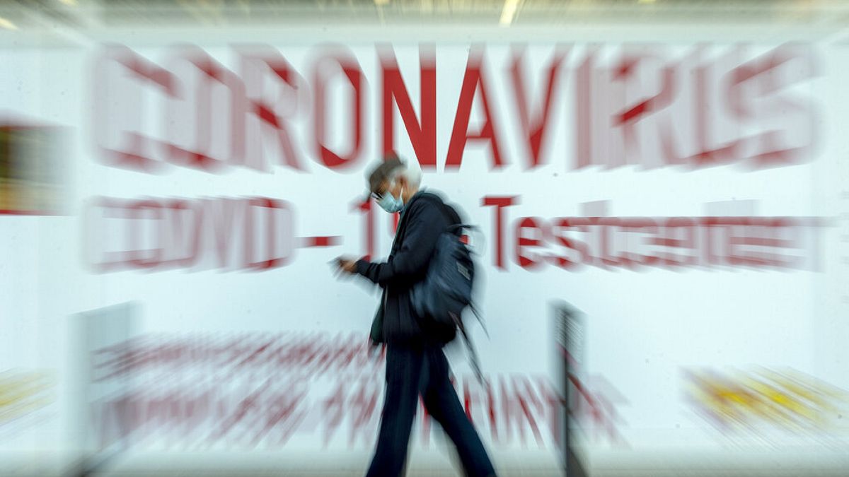 FILE PHOTO: A man walks by a sign in the window of a Coronavirus testing center in Frankfurt, Germany, Thursday, Feb. 25, 2021.