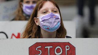 Women, wearing masks against the COVID-19 infection that read "Feminist Solidarity", hold banners during a protest in Bucharest, Romania, Sunday, Oct. 25, 2020.