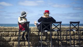 Women sit in a caffe-bar overlooking the Mediterranean Sea as restrictions are eased following months of shutdowns, in Tel Aviv, Israel, Sunday, March 7, 2021