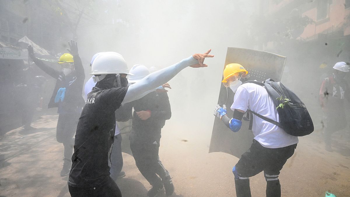 Protesters react after tear gas is fired by police during a demonstration against the military coup in Yangon on March 7, 2021.