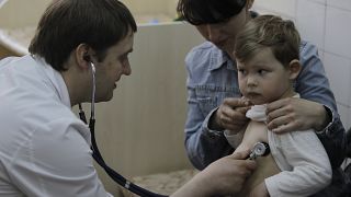 Врач-педиатр Федор Лапий осматривает ребенка перед введением вакцины в Киеве, Украина. 23 апреля 2013 г.