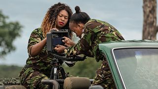 Two rangers set up a mobile camera on the back of a 4x4. 