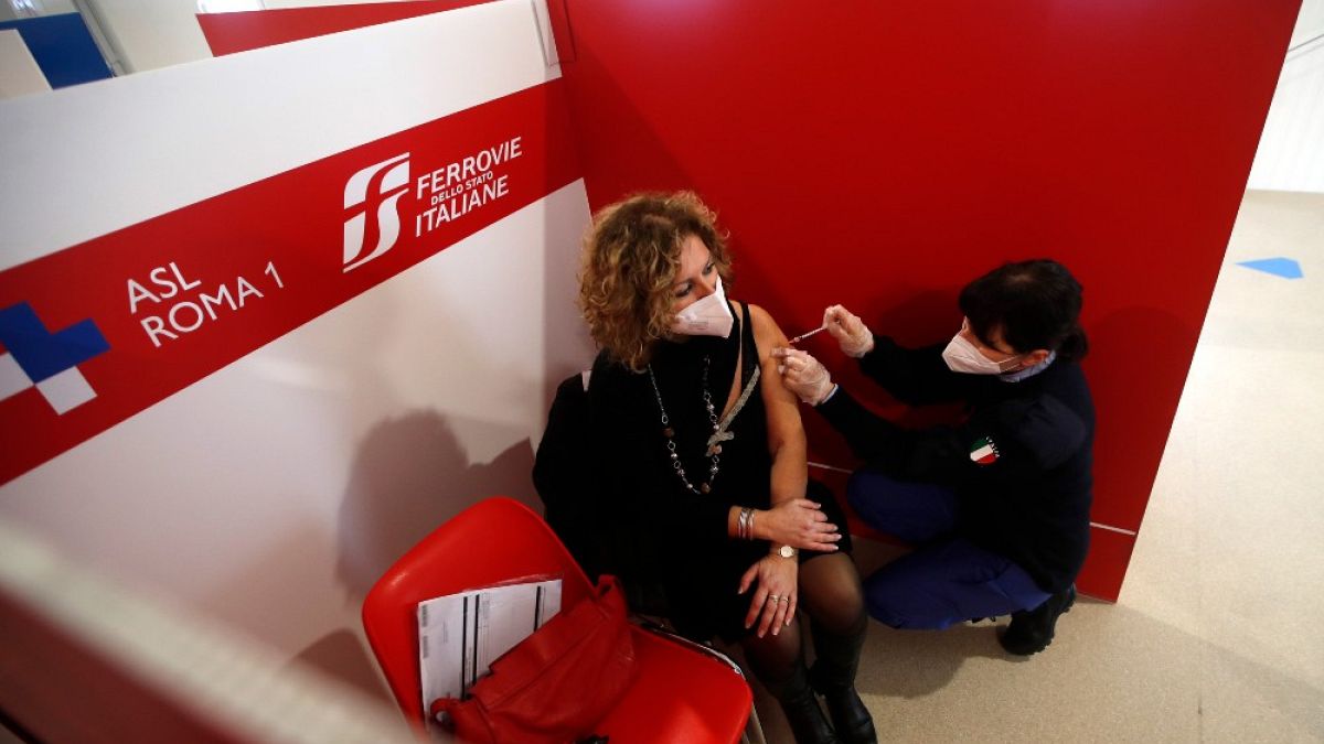 Un operatore sanitario somministra una dose di vaccino AstraZeneca a una donna, in un centro di vaccinazione allestito alla stazione Termini di Roma