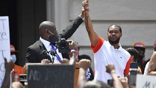 Attorney Benjamin Crump, left, holds up the hand of Kenneth Walker during a rally on the steps of the Kentucky State Capitol in Frankfort, Ky., Thursday, June 25, 2020.