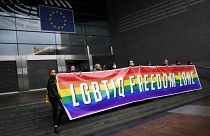 Activists hold a rainbow banner in front of the European Parliament in Brussels on Tuesday ahead of the debate.