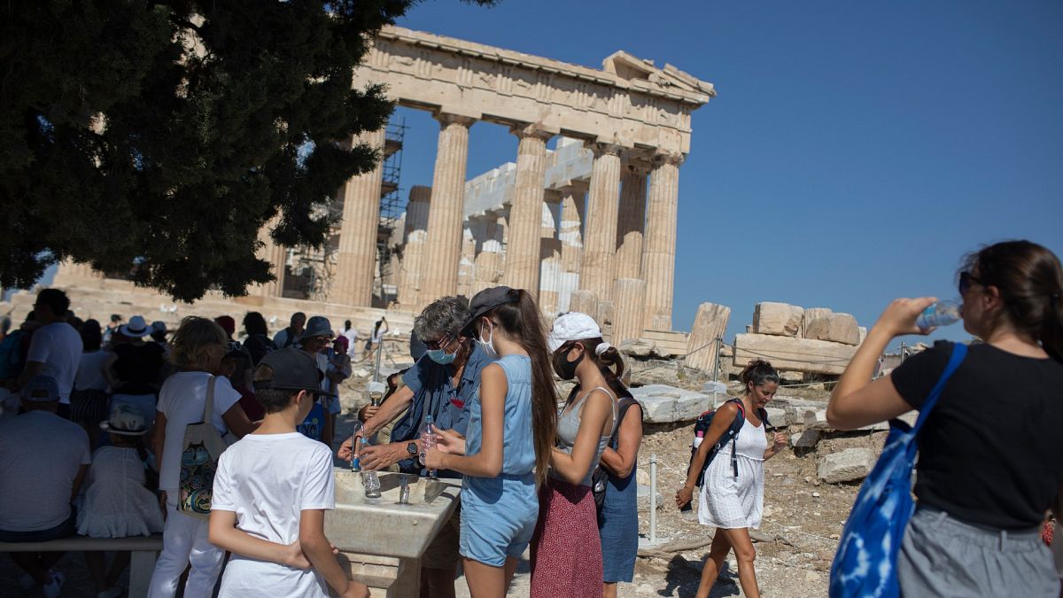 Tourists fill up their water bottles, in front of the ancient temple of Parthenon at Acropolis Hill, in Athens, July 31, 2020.