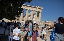 Tourists fill up their water bottles, in front of the ancient temple of Parthenon at Acropolis Hill, in Athens, July 31, 2020.