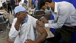 A man reacts while receiving a Sinopharm coronavirus vaccine from a health worker at a vaccination center, in Karachi, Pakistan, Wednesday, March 10, 2021