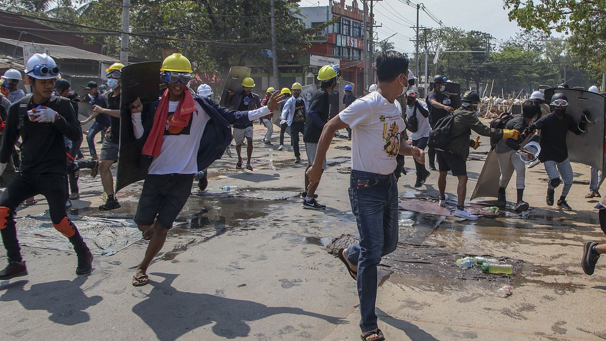 Anti-coup protesters retreat from the frontlines after riot policemen fire sound-bombs and rubber bullets in Yangon, Myanmar, Thursday, March 11, 2021. 