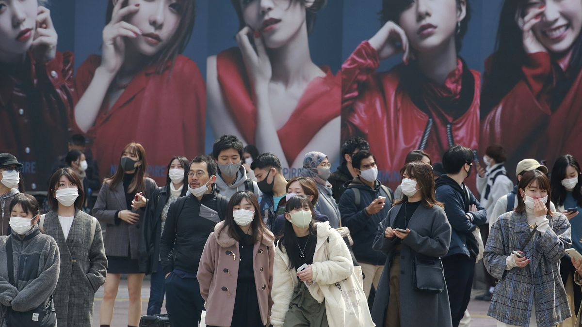 People wearing face masks to protect against the spread of the coronavirus wait at an intersection in Tokyo, Tuesday, March 9, 2021. (AP Photo/Koji Sasahara)