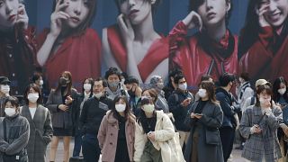 People wearing face masks to protect against the spread of the coronavirus wait at an intersection in Tokyo, Tuesday, March 9, 2021. (AP Photo/Koji Sasahara)