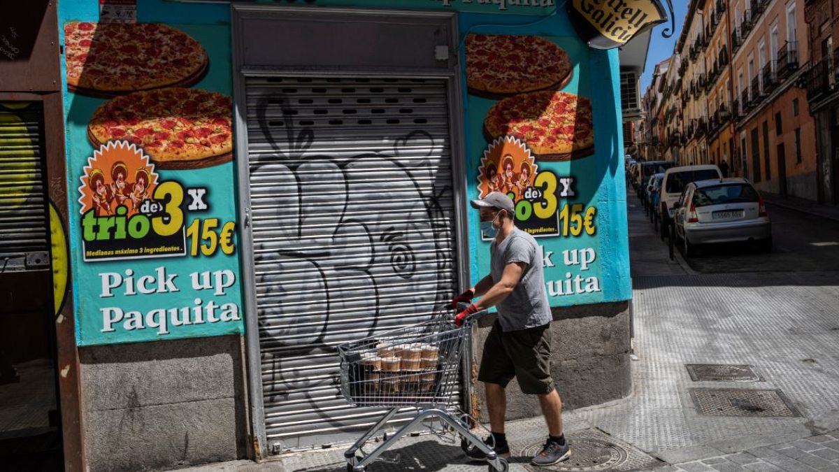Archivo. Un hombre pasa por delante de un comercio cerrado. Madrid, España